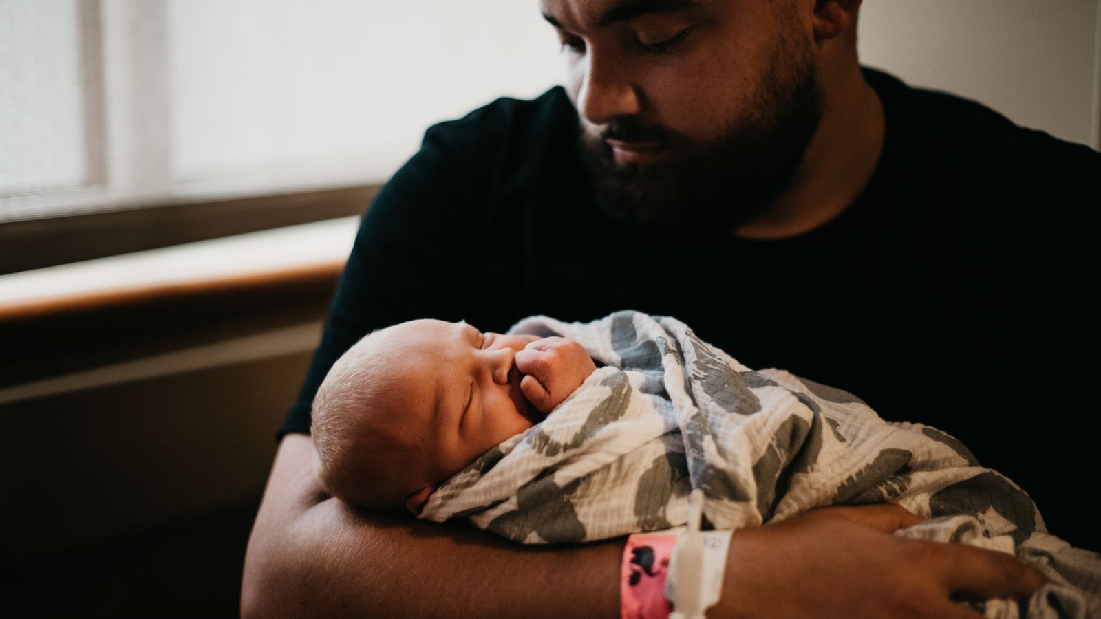 Vater hält ein neugeborenes Baby im Arm