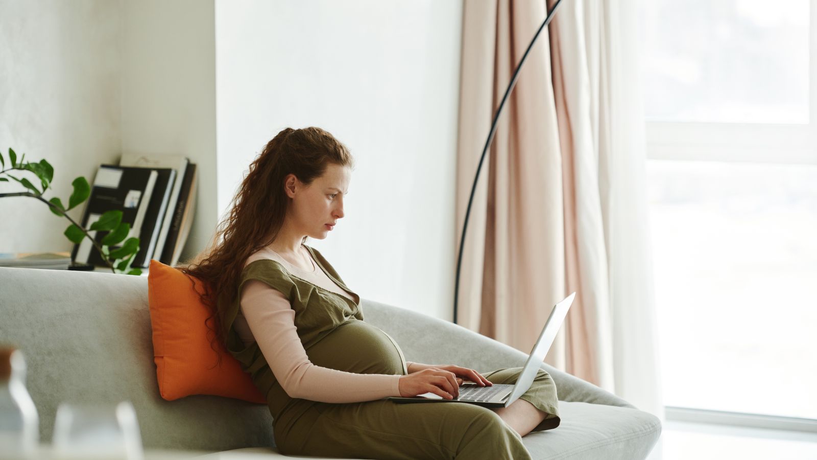 Schwangere Frau arbeitet am Laptop